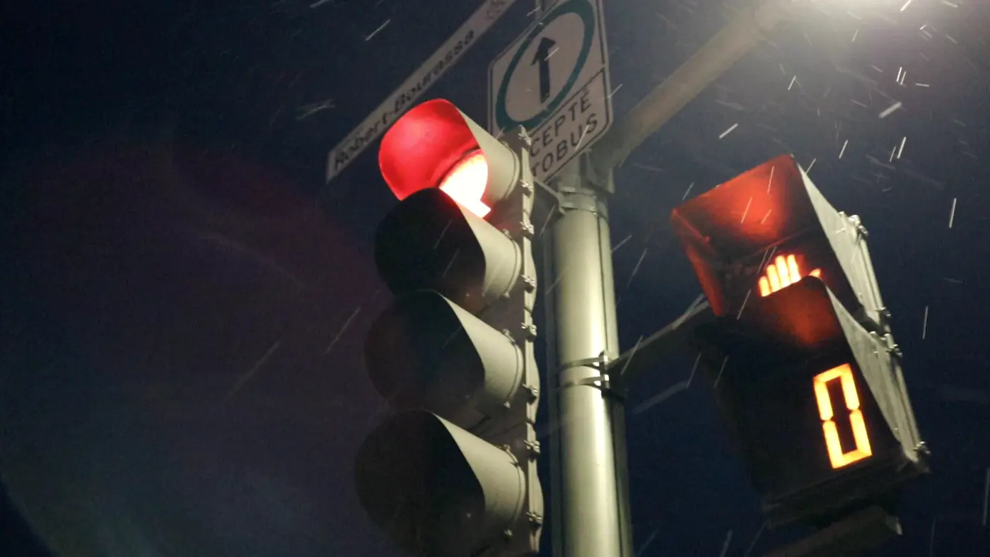 A red pedestrian signal counting down to zero in the snow